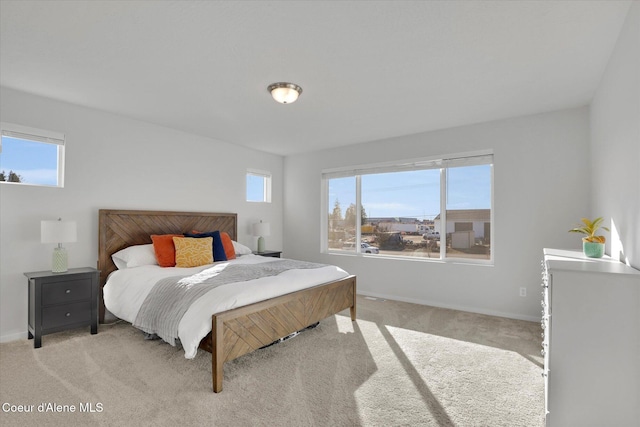 bedroom with multiple windows, baseboards, and light carpet