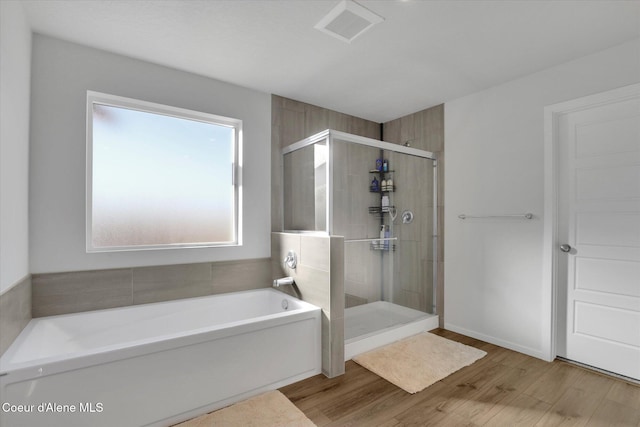 full bathroom featuring visible vents, a stall shower, a garden tub, and wood finished floors