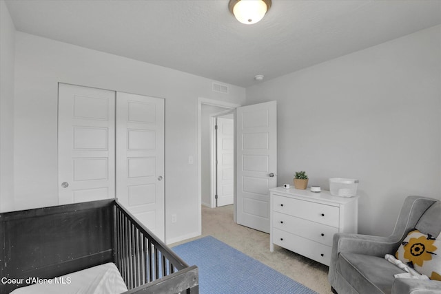 carpeted bedroom with visible vents, baseboards, and a closet