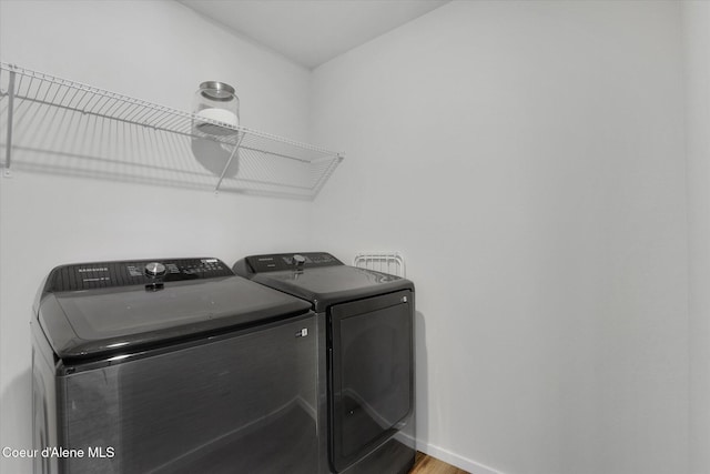 washroom featuring laundry area, wood finished floors, separate washer and dryer, and baseboards