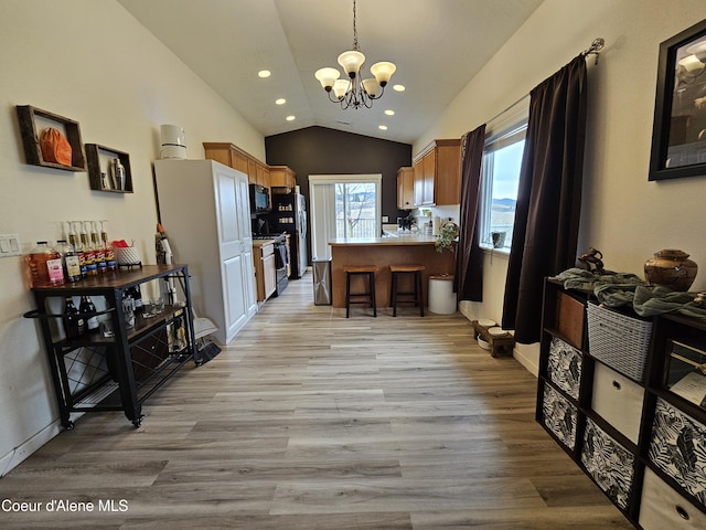 4346 N Brookie Dr, Post Falls, ID 83854 - kitchen with light wood-style flooring, a peninsula, an inviting chandelier, black appliances, and vaulted ceiling