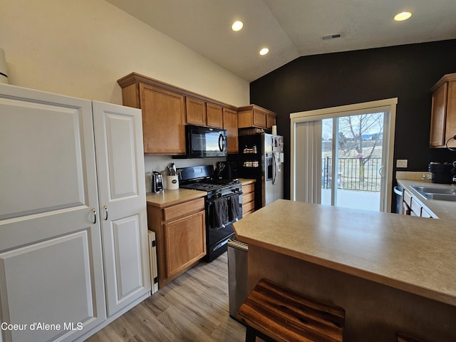 4346 N Brookie Dr, Post Falls, ID 83854 - kitchen with light countertops, lofted ceiling, light wood-style floors, black appliances, and brown cabinetry