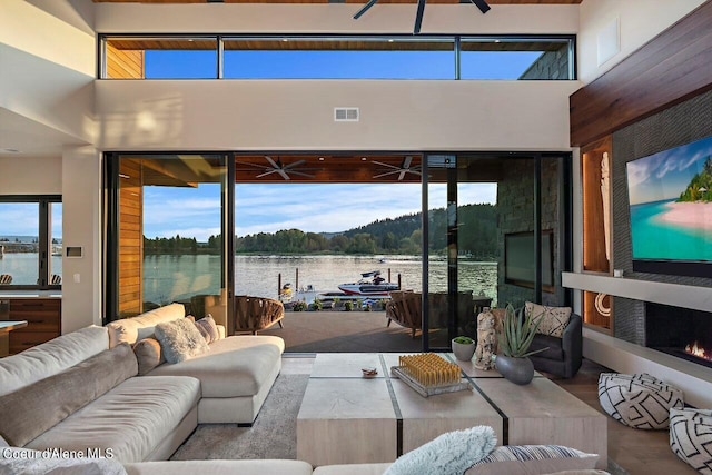 living room featuring visible vents, a healthy amount of sunlight, a towering ceiling, and ceiling fan