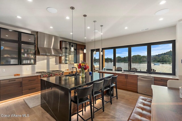 kitchen featuring visible vents, modern cabinets, a sink, light wood-style floors, and wall chimney exhaust hood