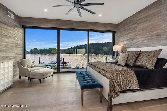 bedroom with access to exterior, multiple windows, wood finished floors, and visible vents