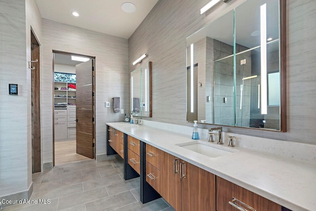 bathroom featuring a walk in closet, a stall shower, a sink, tile walls, and double vanity