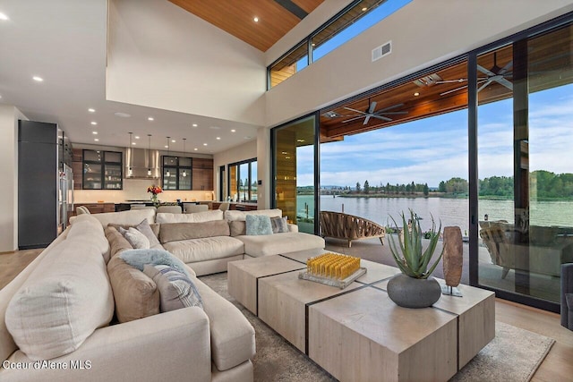 living area featuring a wealth of natural light, visible vents, a water view, and light wood-style flooring