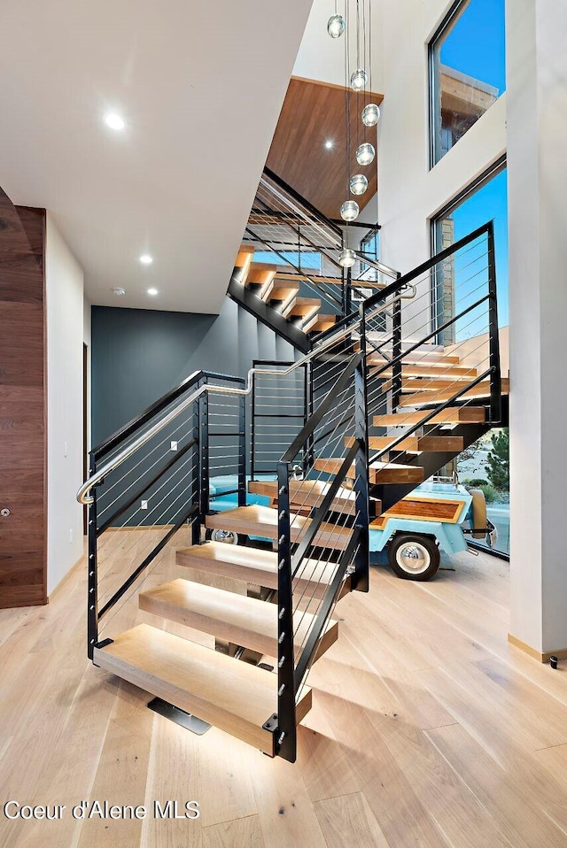 stairs with a high ceiling, recessed lighting, and wood finished floors