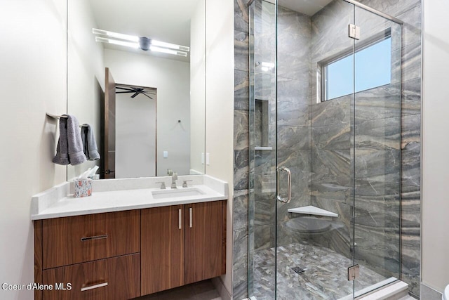 bathroom featuring a ceiling fan, vanity, and a shower stall