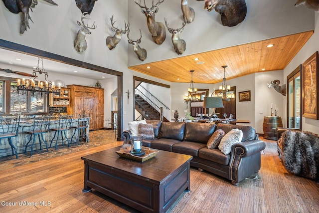 living room featuring hardwood / wood-style floors, recessed lighting, an inviting chandelier, wood ceiling, and stairs