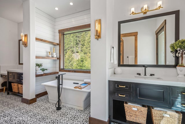 bathroom with vanity, a freestanding tub, wooden walls, and recessed lighting