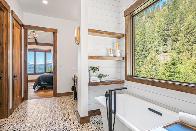 ensuite bathroom featuring a freestanding tub, wood walls, and ensuite bathroom