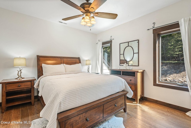 bedroom with visible vents, a ceiling fan, baseboards, and hardwood / wood-style flooring