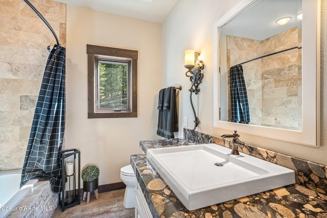 full bathroom featuring toilet, wood finished floors, tiled shower / bath combo, baseboards, and vanity