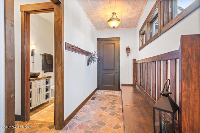 entryway featuring stone tile floors, wood ceiling, and baseboards