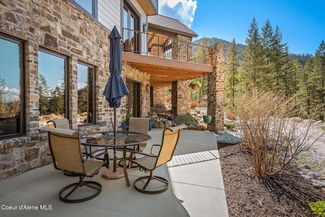 view of patio featuring a balcony and outdoor dining area