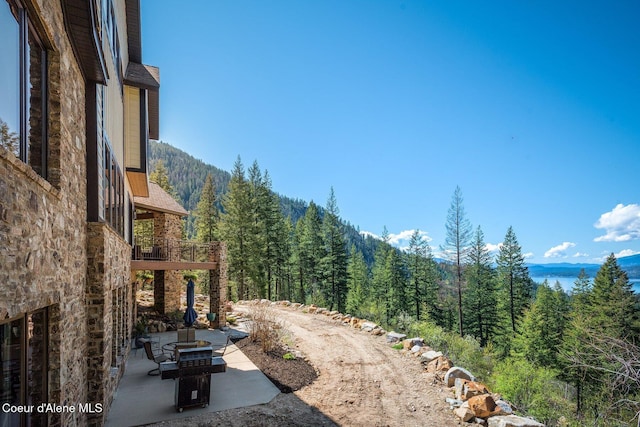 view of yard with a balcony, a patio area, and a forest view