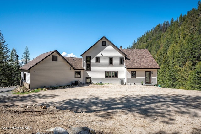 rear view of house with a shingled roof and central AC