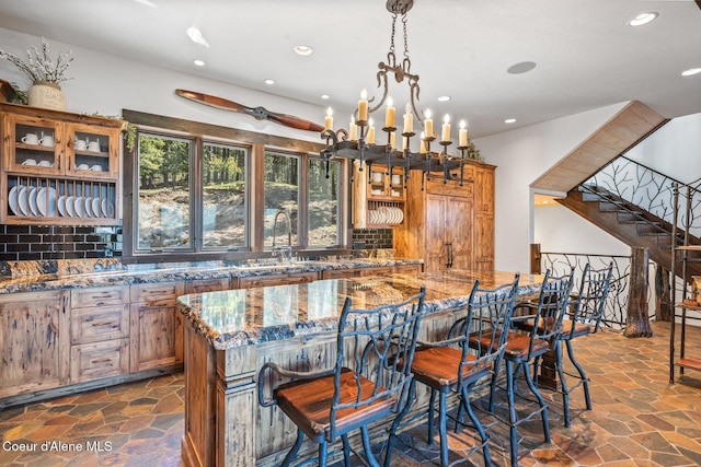 kitchen with stone tile floors, tasteful backsplash, brown cabinets, and a sink