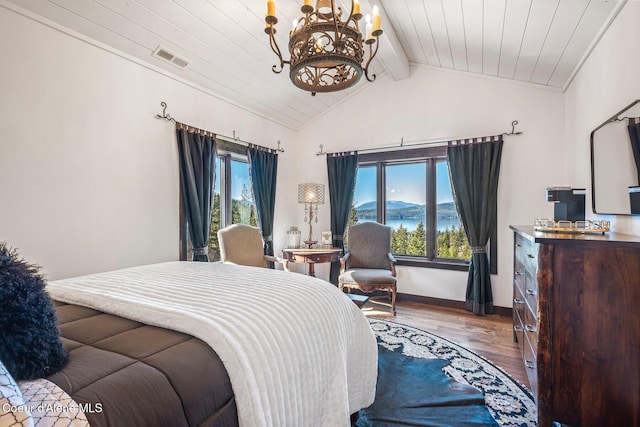 bedroom featuring visible vents, multiple windows, wood finished floors, and vaulted ceiling with beams