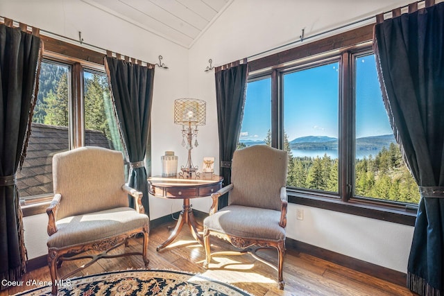 sitting room with vaulted ceiling, wood finished floors, baseboards, and a water view