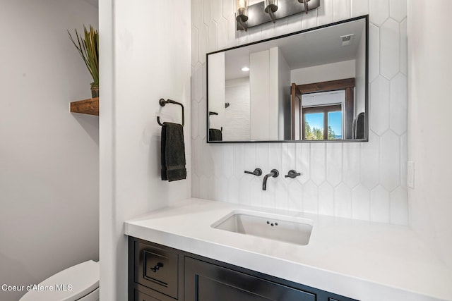 bathroom featuring backsplash, visible vents, toilet, and vanity