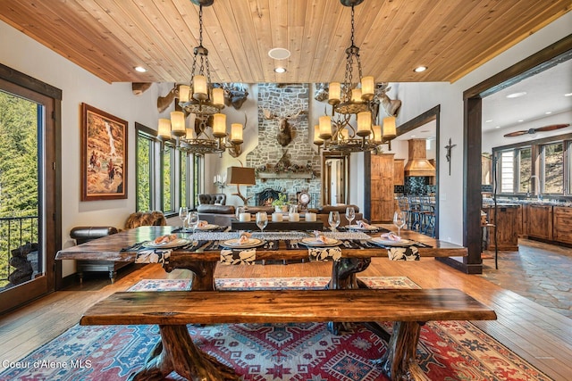 dining space with a notable chandelier, a fireplace, wood ceiling, and hardwood / wood-style floors