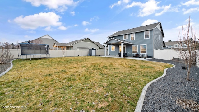 back of property with a trampoline, a patio area, a yard, and a fenced backyard