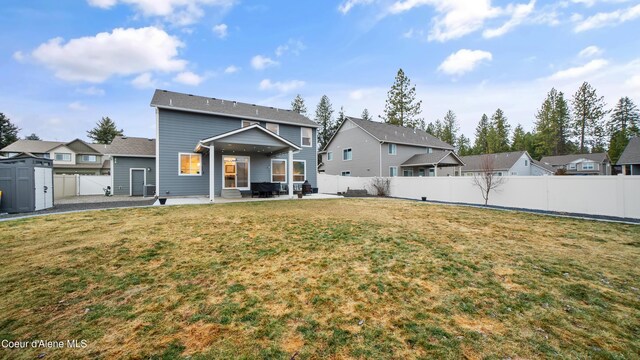 rear view of property featuring a patio, a fenced backyard, a lawn, and a residential view