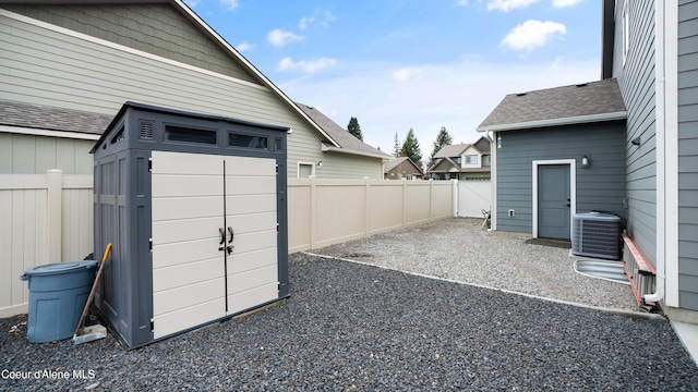 view of yard with a storage shed, an outdoor structure, central air condition unit, and a fenced backyard