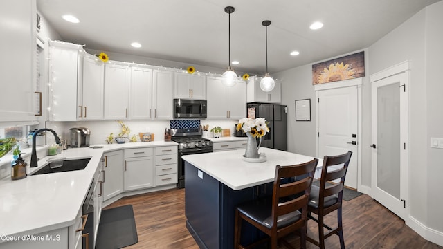 kitchen featuring freestanding refrigerator, a sink, light countertops, dark wood-type flooring, and gas range