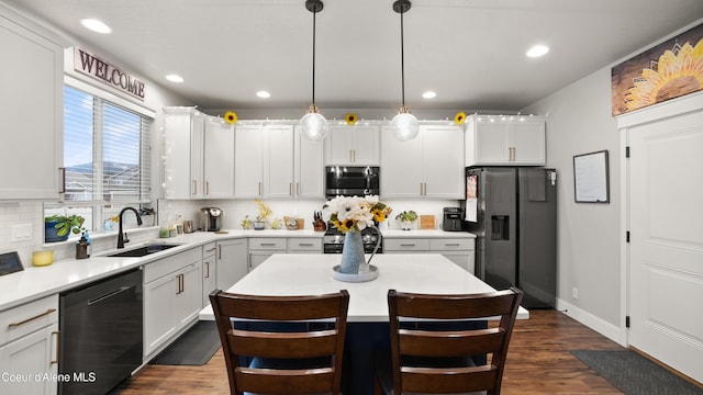 kitchen with a sink, backsplash, dark wood-style floors, appliances with stainless steel finishes, and light countertops