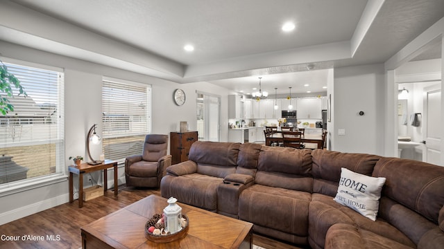 living area featuring recessed lighting, baseboards, dark wood-type flooring, and an inviting chandelier