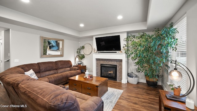 living room with recessed lighting, a tray ceiling, wood finished floors, and a tile fireplace