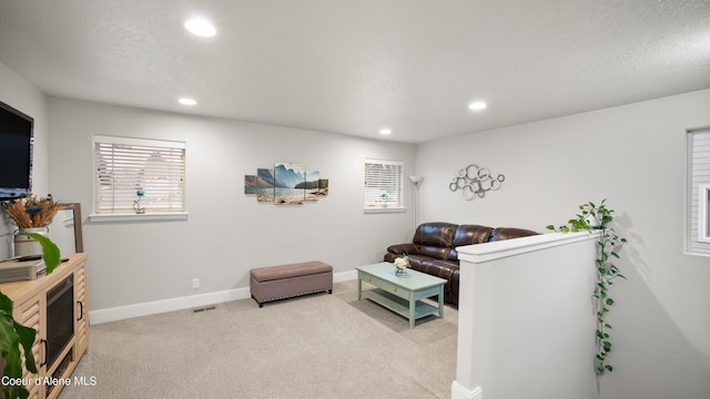 living room featuring visible vents, baseboards, recessed lighting, a textured ceiling, and light colored carpet