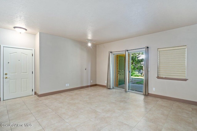 spare room with baseboards and a textured ceiling