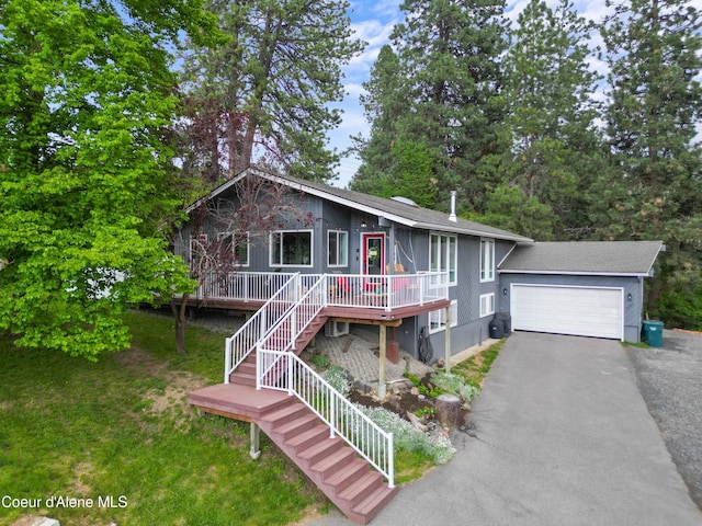 chalet / cabin with stairs, aphalt driveway, an attached garage, and a front yard