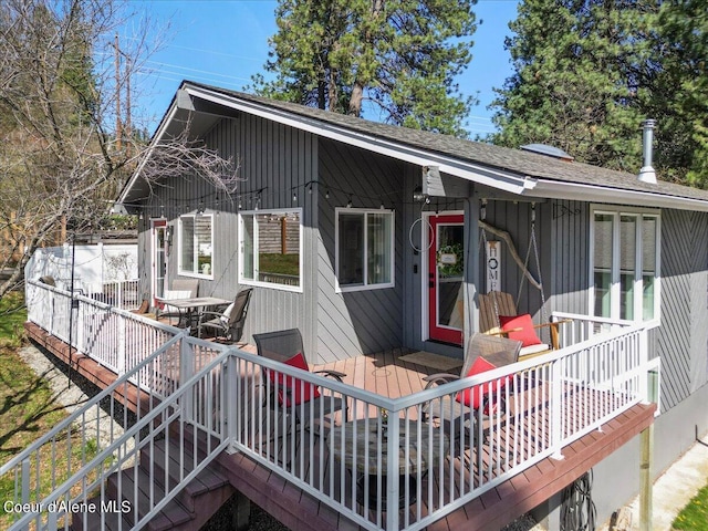 exterior space with a shingled roof and a deck