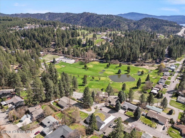 drone / aerial view featuring a mountain view, a view of trees, and golf course view