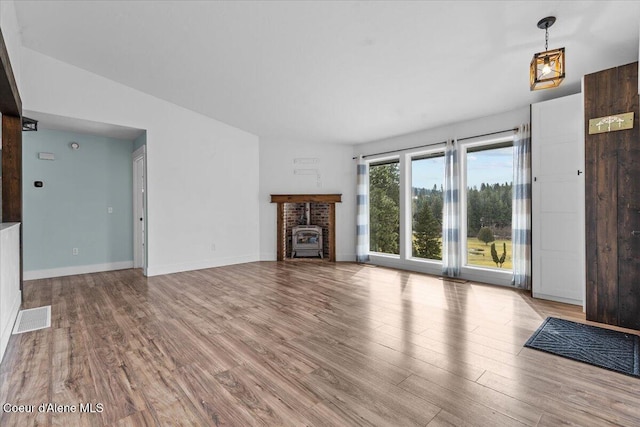 unfurnished living room featuring a fireplace, wood finished floors, visible vents, and baseboards