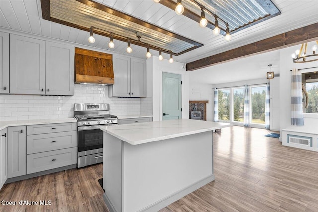 kitchen with stainless steel gas range oven, dark wood finished floors, light countertops, decorative backsplash, and gray cabinets