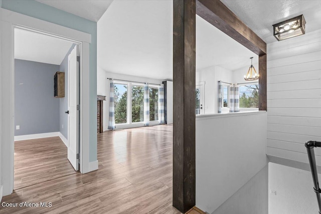 hallway with beamed ceiling, wood finished floors, and a wealth of natural light