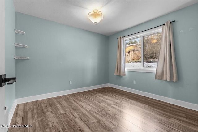 unfurnished room featuring baseboards and wood finished floors