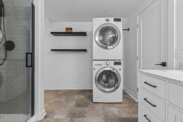 washroom featuring baseboards, a textured ceiling, and stacked washer and clothes dryer