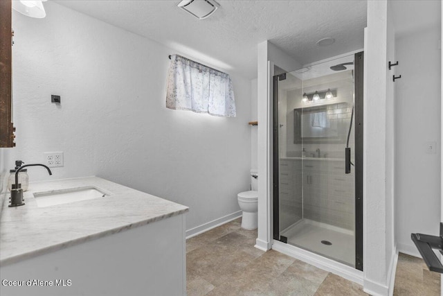 bathroom featuring a shower stall, baseboards, toilet, vanity, and a textured ceiling