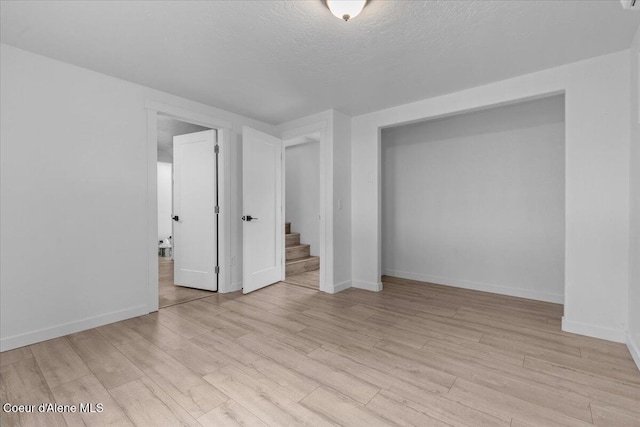 interior space with baseboards, light wood finished floors, and a textured ceiling