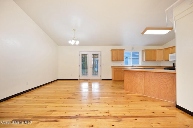 kitchen with white microwave, light brown cabinets, lofted ceiling, light wood-style flooring, and a peninsula