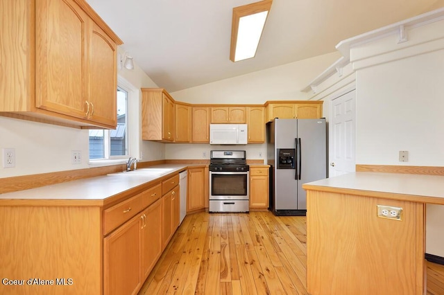 kitchen with light wood finished floors, light countertops, a peninsula, stainless steel appliances, and a sink