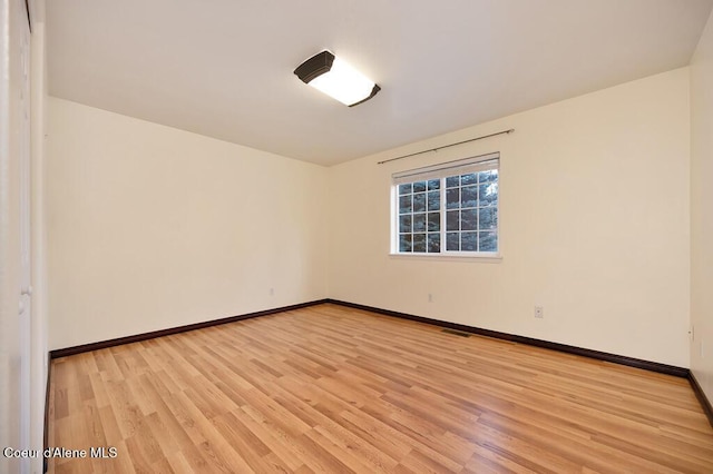 unfurnished room with baseboards, visible vents, and light wood-type flooring