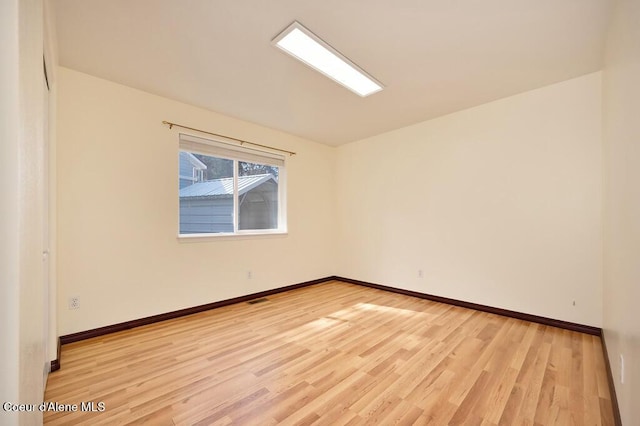 unfurnished room featuring visible vents, light wood-style floors, and baseboards